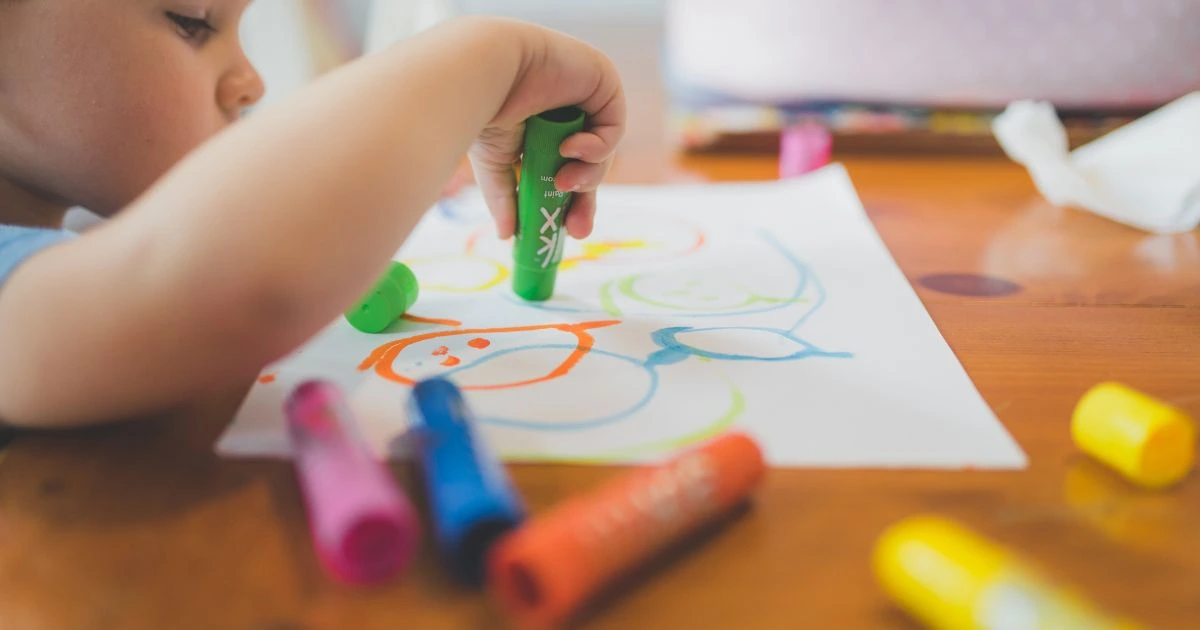 Child drawing on paper on a wooden table